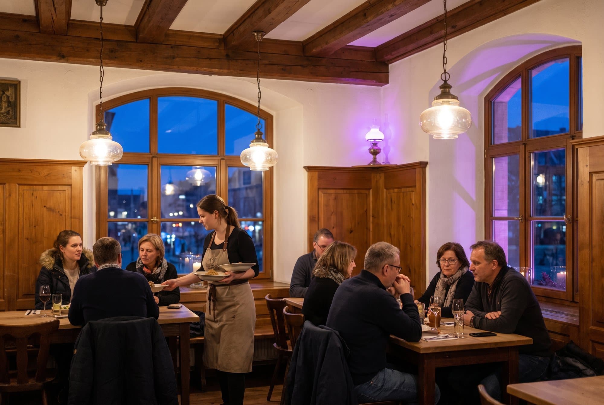 Rahvast täis restoran lõuna ajal, ettekandja toob roogi puidust laudade juurde